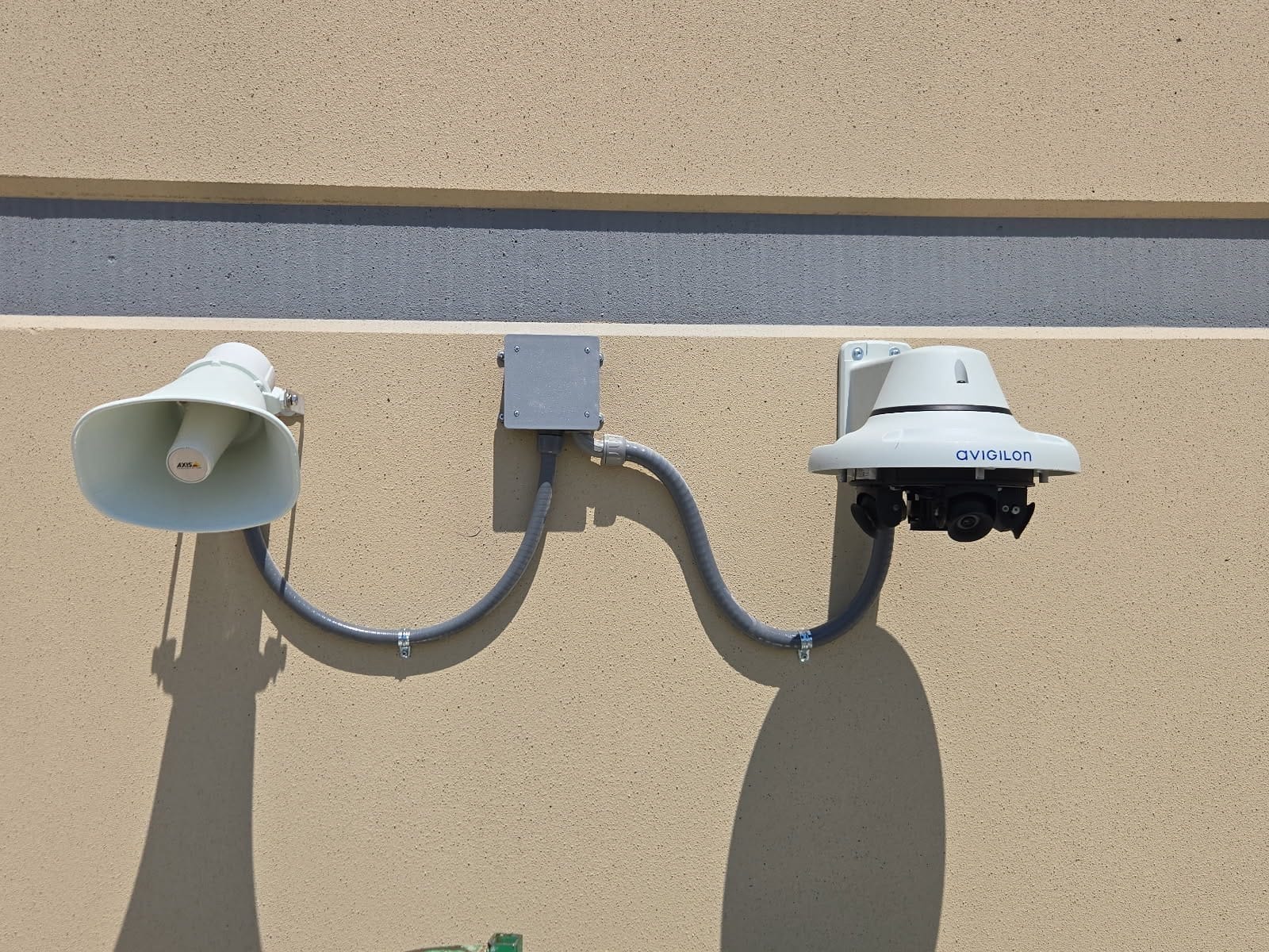 Avigilon dome camera, speaker and junction box on an exterior wall