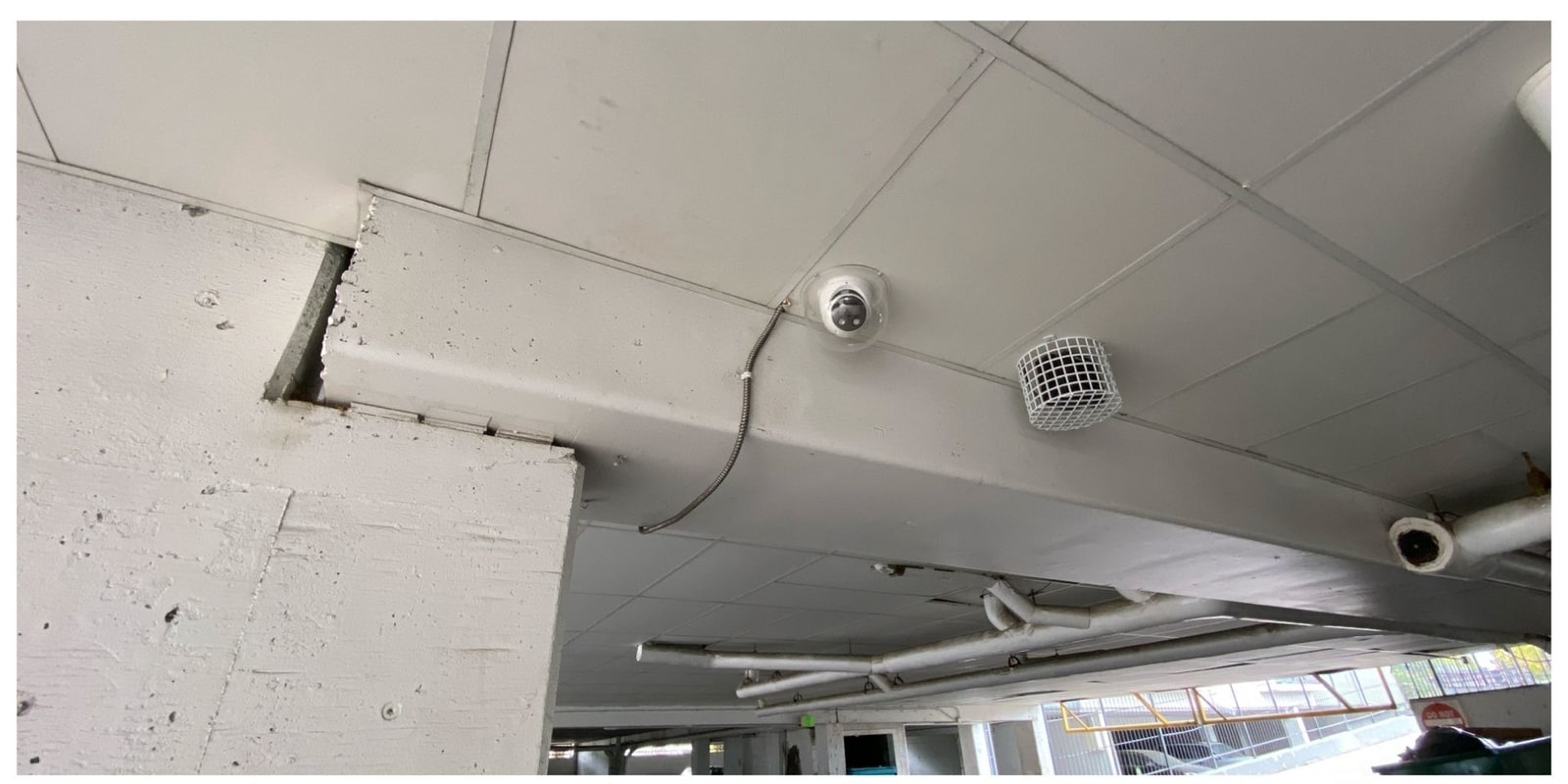 Ceiling dome camera and surface conduit in a covered parking structure at Avantus Apartments