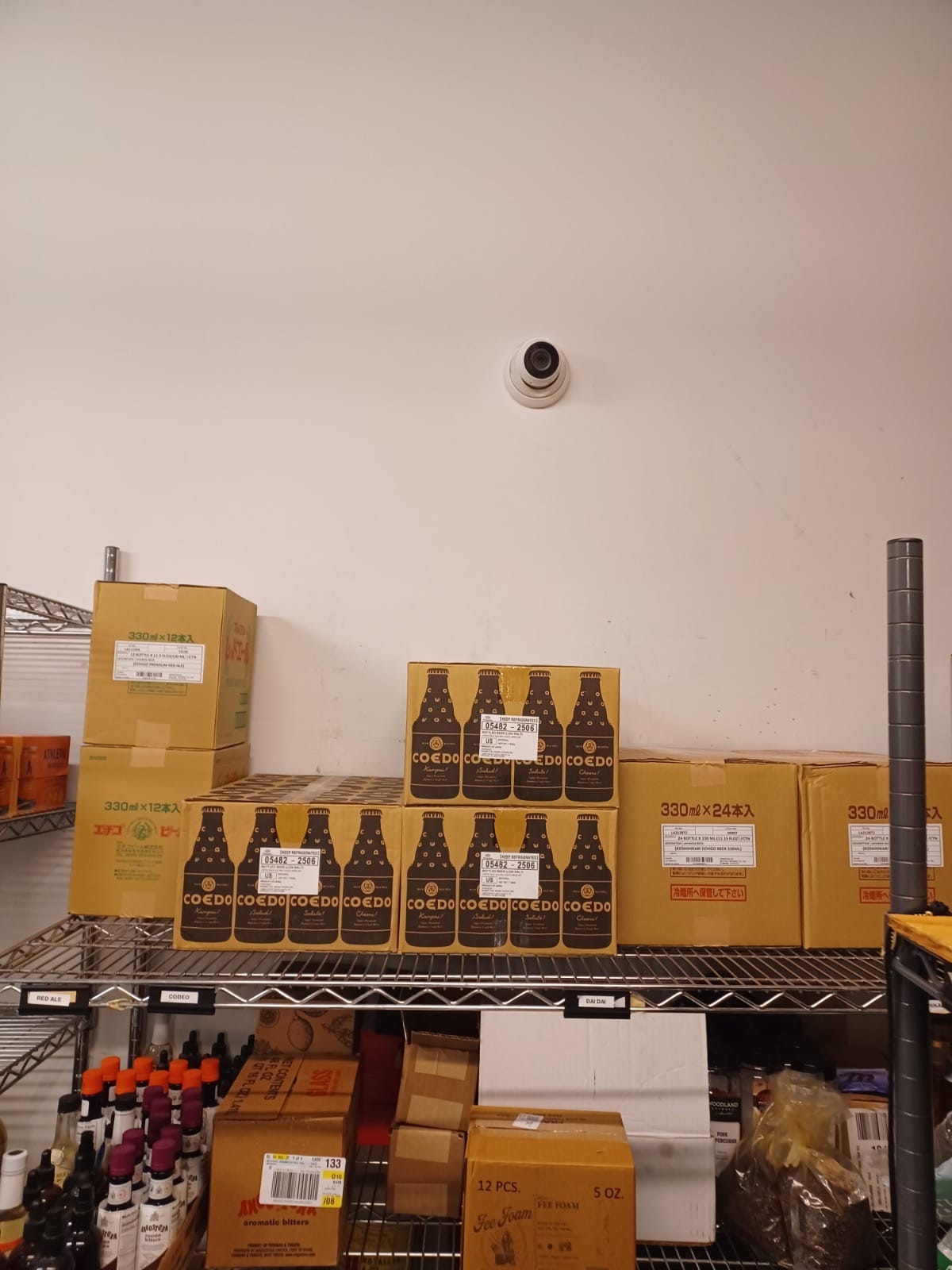 Security camera monitoring high-value inventory and dry storage at Sushi Den restaurant