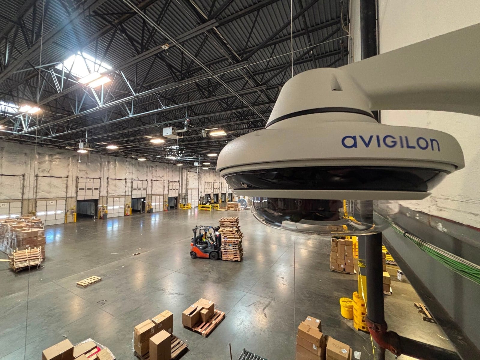 Avigilon multi-sensor camera looking over a warehouse floor with dock doors, racking and a forklift