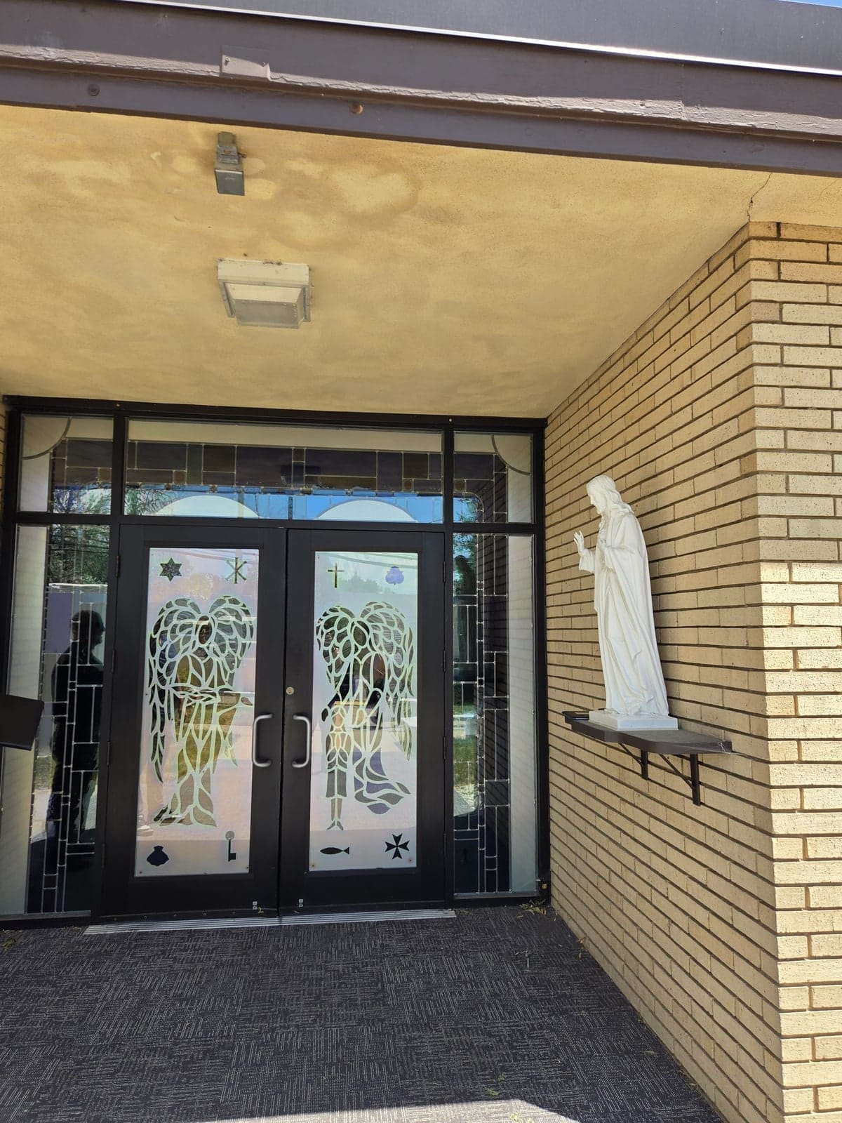 Covered chapel entrance with stained-glass double doors and a lit soffit at Denver Children's Home